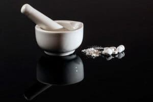 A mortar and pestle and white pills that may be part of a case for a medical device and drug injury lawyer